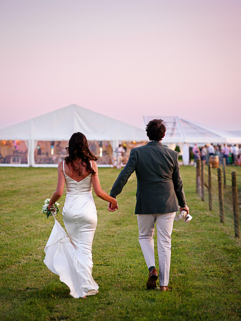 Couple walking to Devon wedding marquee at sunset